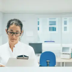Okulistka w białym fartuchu notuje coś na kartce. Zastanawiasz się, ile zarabia okulista prywatnie?