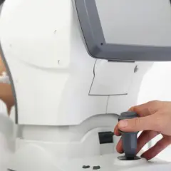 Pacjentka poddawana komputerowemu badaniu wzroku. Lekarz obsługuje urządzenie.