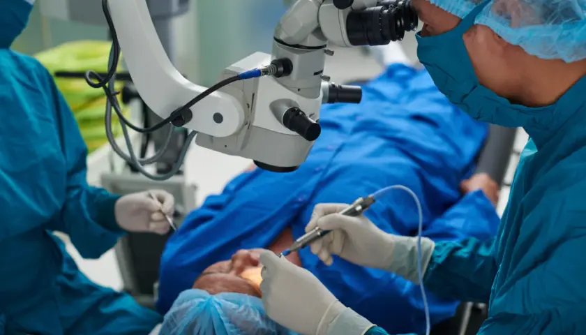 Chirurg wykonuje przeszczep rogowki, używając mikroskopu operacyjnego. Pacjent leży pod znieczuleniem.