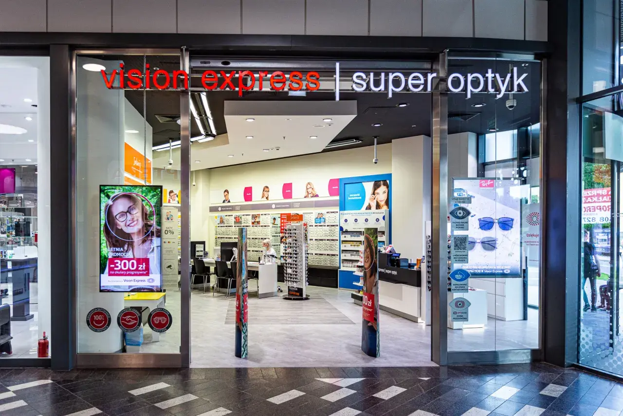 Wejście do salonu Vision Express z ekspozycją okularów i reklamą promocji.